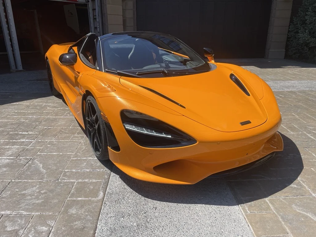 McLaren 750S Spider in Papaya orange, front three quarter view with the roof stowed